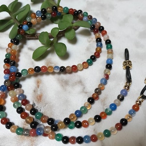 May include: A multi-colored beaded eyeglass chain with black, red, orange, yellow, green, blue, and white beads. The chain has gold-toned metal clasps and a black cord.