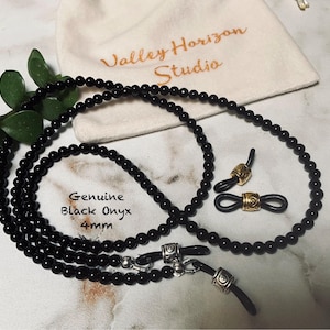May include: Black onyx bead glasses chain with gold-toned metal clasps. The chain is 4mm in diameter and is displayed on a white surface with a small bag that says "Valley Horizon Studio".