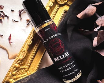 May include: A 10 ml rollerball perfume bottle with a black cap and a black and red label. The label reads "Evil's Advocate" and "Belial Devotional Fragrance".
