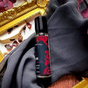 May include: A black and red roll-on bottle of perfume with the text "The Oath" and "Original Essence Perfume" on the label.