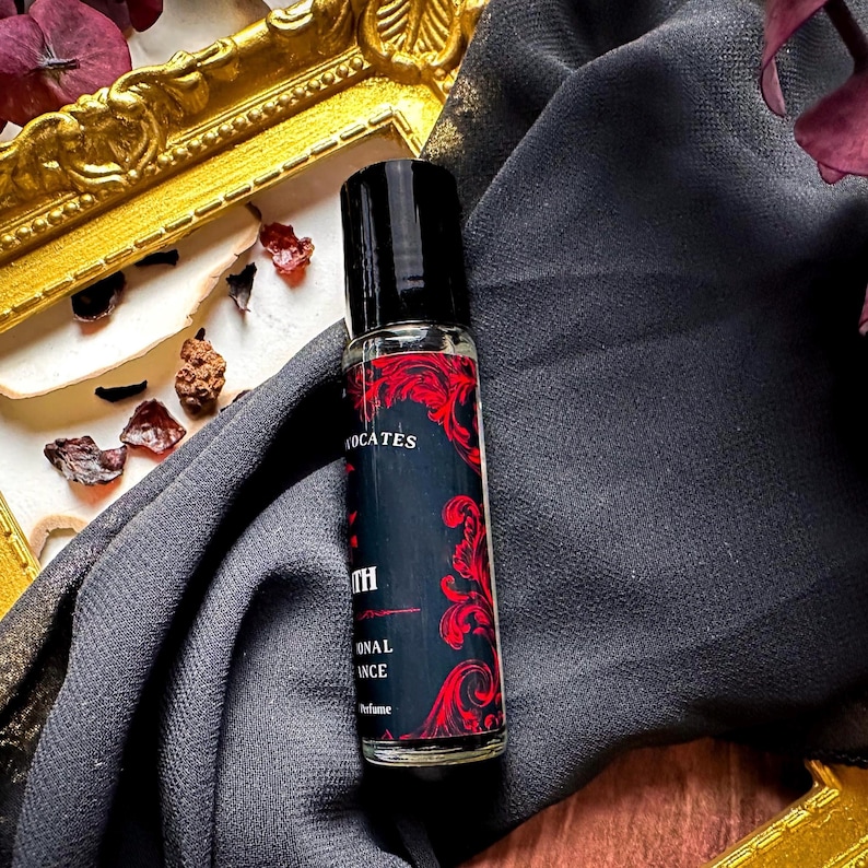 May include: A black and red roll-on bottle of perfume with the text "The Oath" and "Original Essence Perfume" on the label.