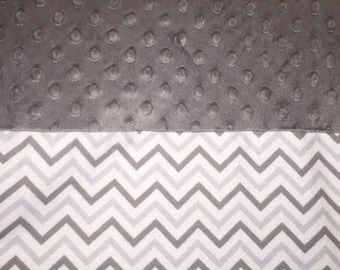 May include: A grey fabric with a textured polka dot pattern and a white and grey chevron pattern.