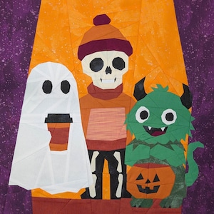 May include: A Halloween quilt depicting a ghost with a coffee cup, a skeleton in a hat, and a green monster with a pumpkin. The background is orange and purple, with a geometric pattern.