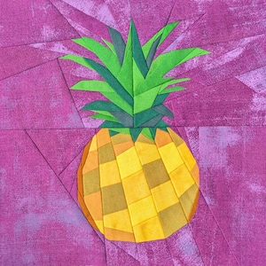 May include: A fabric quilt block featuring a pineapple design constructed from geometric yellow and orange patches. The pineapple has green leaves made of angular fabric pieces, all set against a textured, solid magenta background fabric.