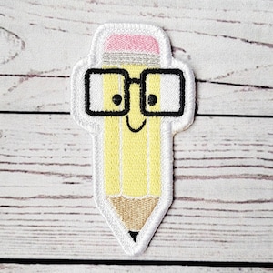 Könnte beinhalten: Ein gelber Bleistift mit einem rosa Radiergummi und einer schwarzen Brille. Der Bleistift hat ein fröhliches Gesicht und ist auf einem weißen Hintergrund gestickt.