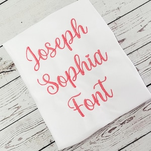May include: White fabric with the names "Joseph" and "Sophia" embroidered in pink cursive font.
