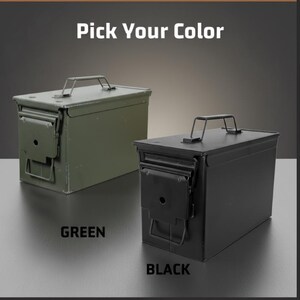 May include: Two rectangular metal ammunition cans with top handles and side latches. One can is olive green and the other is matte black. The text "Pick Your Color" appears at the top, with the words "GREEN" and "BLACK" below each respective can.