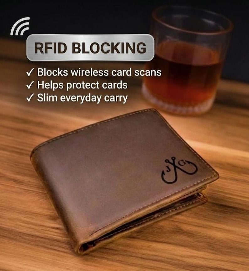 May include: A brown leather bifold wallet featuring a dark engraved logo of two crossed fishing hooks with the letters J and G. Text above reads RFID BLOCKING, Blocks wireless card scans, Helps protect cards, and Slim everyday carry.
