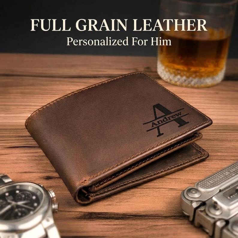 May include: A brown full grain leather bifold wallet featuring a dark engraved monogram with a large letter A and the name Andrew centered across it. The text FULL GRAIN LEATHER Personalized For Him is visible above the wallet.
