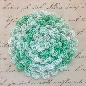 May include: A white ceramic mug with a black handle and the text "But First, Coffee" in a bold, black font. The mug is set against a blurred background, suggesting a cozy setting.