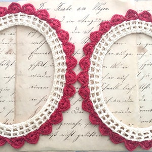 Peut inclure: Deux cadres ovales en crochet présentant une bordure intérieure en treillis couleur crème et un bord extérieur festonné en fil rouge foncé. Le motif se compose d'une grille centrale ouverte entourée d'un point décoratif en forme de coquille.