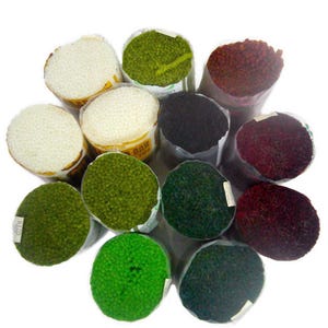 May include: A collection of colorful rug yarn bundles in various shades, including white, green, black, and burgundy. The yarn is tightly wound and packaged in clear plastic, showcasing the texture and color variations. Ideal for crafting and rug making projects.