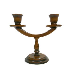 May include: A wooden candle holder with two candle cups. The candle holder has a curved arm connecting the two cups, and a round base. The wood has a dark brown finish.