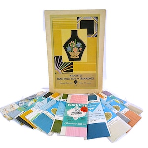 May include: Vintage sewing supplies featuring a booklet titled "Wright's Bias Fold Tape and Trimmings" with a floral vase design. Assorted packages of seam binding in various colors are fanned out below the booklet.