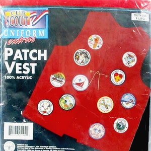 May include: Red Cub Scout uniform patch vest with various embroidered patches, including "Discover", "Yellow Lakes", "Black Creek", and "Sea Scout World". The vest is made of 100% acrylic and is youth size X-Large.