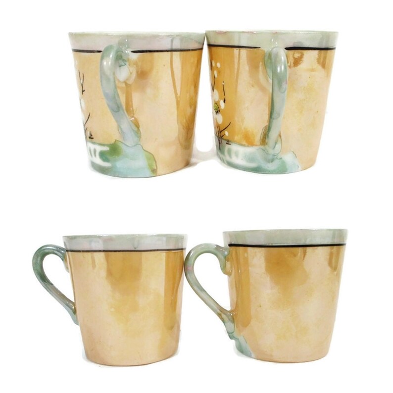 Pode incluir: Conjunto de quatro ch&aacute;venas de ch&aacute; vintage com um design floral. As ch&aacute;venas s&atilde;o feitas de porcelana e t&ecirc;m um esmalte castanho claro com uma borda verde. O design floral est&aacute; em tons de branco e castanho.