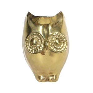 May include: A gold-colored metal owl figurine with detailed eyes. The owl is standing on a white background.