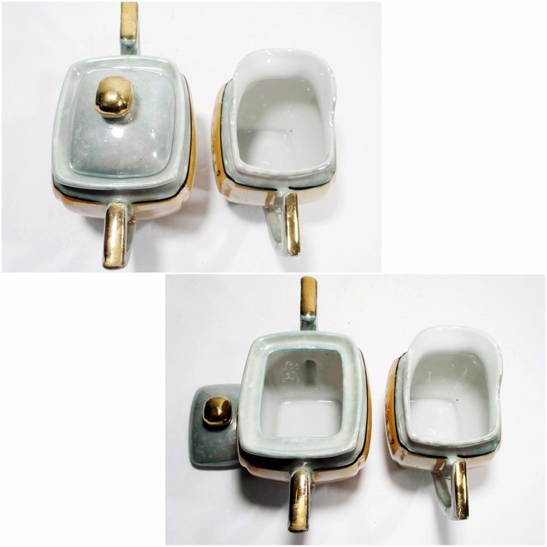 Pode incluir: Um conjunto de dois recipientes de creme e a&ccedil;&uacute;car de cer&acirc;mica vintage com detalhes dourados. Os recipientes s&atilde;o quadrados com um esmalte azul claro e branco. As tampas t&ecirc;m um bot&atilde;o dourado.