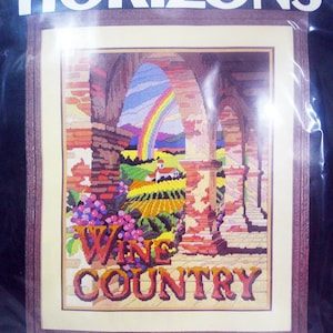 May include: A framed longstitch kit titled "Wine Country." The design features a colorful landscape with a rainbow, vineyards, and the words "Wine Country." The design size is approximately 16" x 20".