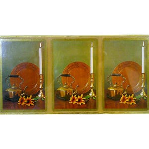 May include: A decorative panel featuring three framed images of a still life. Each image includes a copper-colored plate, a gold teapot, a lit candle in a gold holder, and yellow flowers. The background is a muted green.