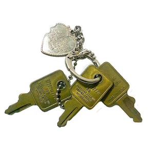 May include: A set of three brass-colored keys on a key ring, with a heart-shaped tag. The keys have text that reads "DENVER, DETROIT, PITTSBURGH" and "MADE IN U.S.A.". The heart tag has text that is difficult to read.
