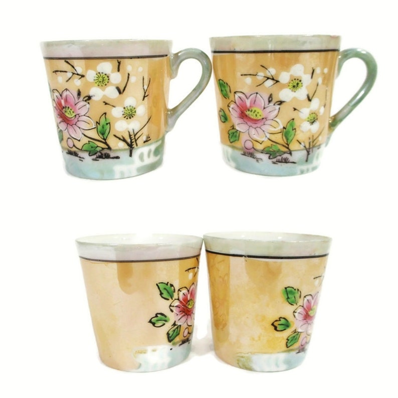 Pode incluir: Conjunto de quatro ch&aacute;venas de ch&aacute; vintage com desenhos florais. As ch&aacute;venas s&atilde;o brancas com um esmalte amarelo claro e apresentam padr&otilde;es florais rosa e verdes. Duas das ch&aacute;venas t&ecirc;m al&ccedil;as.