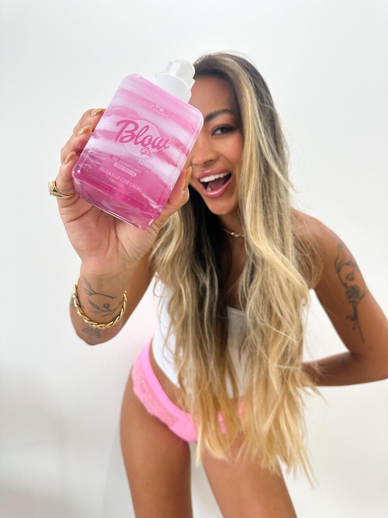 May include: A clear pink bottle with a white pump top and the text "Blow Girl" in pink. The bottle is labeled "Gel Arom&aacute;tico para Banho" and "Hidrata&ccedil;&atilde;o com Creme".