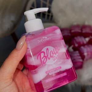 May include: A pink and white bottle of "Blow Girl" body gel with a pump dispenser. The bottle is labeled "Gel Aromatizante Para Virilha" and "Morango Com Creme" and contains 320 ml of product.