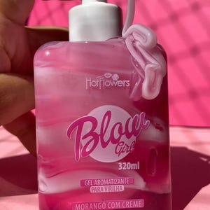May include: A pink bottle of gel with a white pump top and a white swirl of gel on the side. The bottle is labeled "Blow Girl 320ml Gel Aromatizante Para Virilha Morango Com Creme".