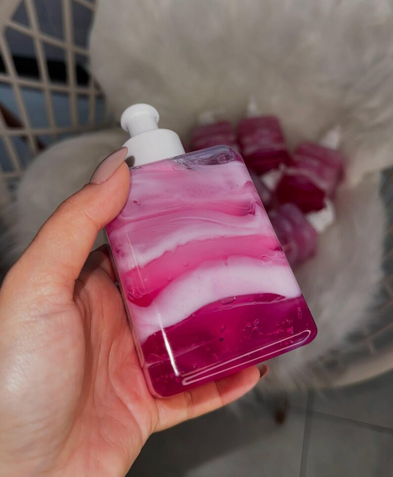 May include: A clear bottle with a white pump dispenser filled with pink and white liquid. The liquid has a marbled appearance.