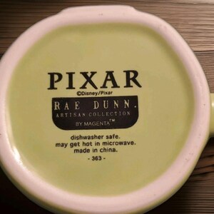 Peut inclure: Le dessous d'une tasse en c&eacute;ramique vert clair avec un texte imprim&eacute; en noir indiquant PIXAR, Disney/Pixar, RAE DUNN. ARTISAN COLLECTION BY MAGENTA, dishwasher safe, may get hot in microwave, made in china, et le num&eacute;ro 363.