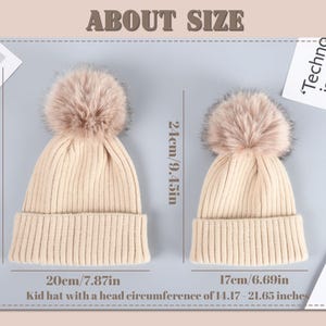 May include: Two beige knit hats with faux fur pom-poms. The larger hat measures 28 inches in circumference and the smaller hat measures 24 inches in circumference.  The text "Kid hat with a head circumference of 14.17-21.65 inches" is below the hats.