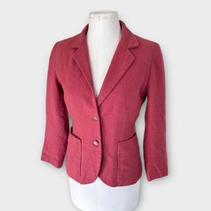 Op de afbeelding: Een rode blazer met twee voorzakken en twee knopen. De blazer wordt gepresenteerd op een witte mannequin. De blazer heeft een klassiek ontwerp met een gekerfde revers en lange mouwen.