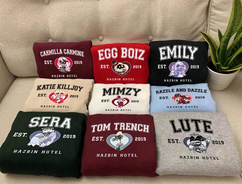 May include: Nine different colored sweatshirts with cartoon character graphics and the text "Hazbin Hotel" printed on each. The characters include Katie Killjoy, Razzle and Dazzle, Mimzy, Tom Trench, Sera, Emily, Egg Boiz, Carmilla Carmine, and Lute.