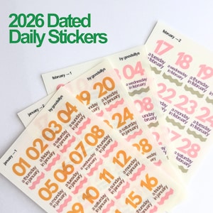 May include: Sheets of 2026 dated daily stickers. The stickers feature dates in orange and pink, with the month and day of the week printed below. The text "2026 Dated Daily Stickers" is in green at the top.