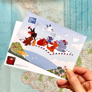 May include: A postcard with a colourful illustration of animals on a paper aeroplane. The postcard has the text "Happy World Postcard Day" and is held in a hand. The background is a map.