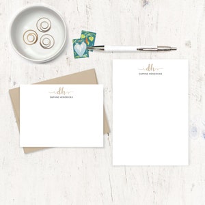 May include: Two white stationery note cards with a brown envelope. The note cards have a gold monogram with the initials "DH" and the name "Daphne Hendricks" printed below the monogram.