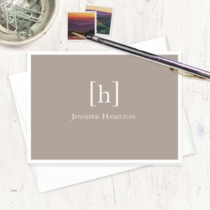 May include: A light brown card with a white border. The card has a white monogram of the letter "h" in a square. The text "Jennifer Hamilton" is printed below the monogram.