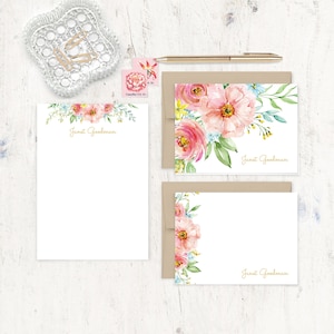 May include: Set of three personalized stationery cards with a floral design. The cards feature a watercolor illustration of pink and yellow flowers with green leaves. The name "Janet Goodman" is printed in gold on each card.