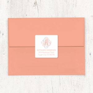 May include: A white square return address label with a gray and peach swirl monogram "A" and the text "KATHLEEN ANDERSON 824 Woodview Place Sugar City CO 8076"