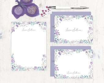 Puede incluir: Conjunto de tres tarjetas de papelería florales moradas con fondo blanco y el nombre "Lauren Sullivan" escrito en cursiva. Las tarjetas tienen un borde de flores y hojas moradas y verdes en acuarela.