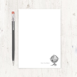 May include: White notepad with a black and white illustration of a globe and the text "the burkes" at the bottom.