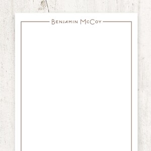 K&ouml;nnte beinhalten: Ein wei&szlig;es Blatt Papier mit einem braunen Rand und dem Text "BENJAMIN MCCOY" oben.