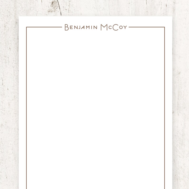 K&ouml;nnte beinhalten: Ein wei&szlig;es Blatt Papier mit einem braunen Rand und dem Text "BENJAMIN MCCOY" oben.