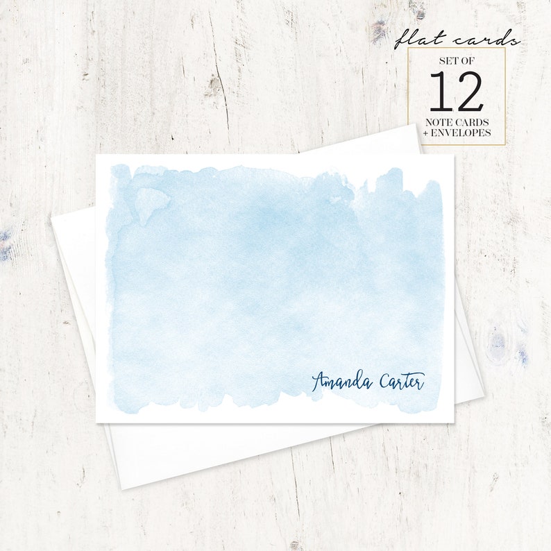 Puede incluir: Un juego de 12 tarjetas de notas de acuarela azul con sobres. Las tarjetas presentan un fondo de acuarela azul claro con el nombre "Amanda Carter" impreso en tinta azul oscuro en la parte inferior.