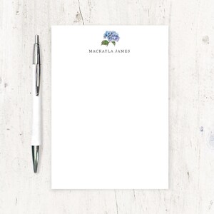 May include: White notepad with a blue hydrangea illustration and the name "Mackayla James" printed at the top.