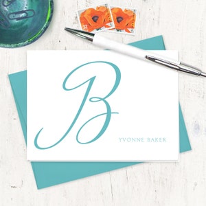 May include: A white card with a teal blue cursive letter "B" and the text "YVONNE BAKER" printed in black.