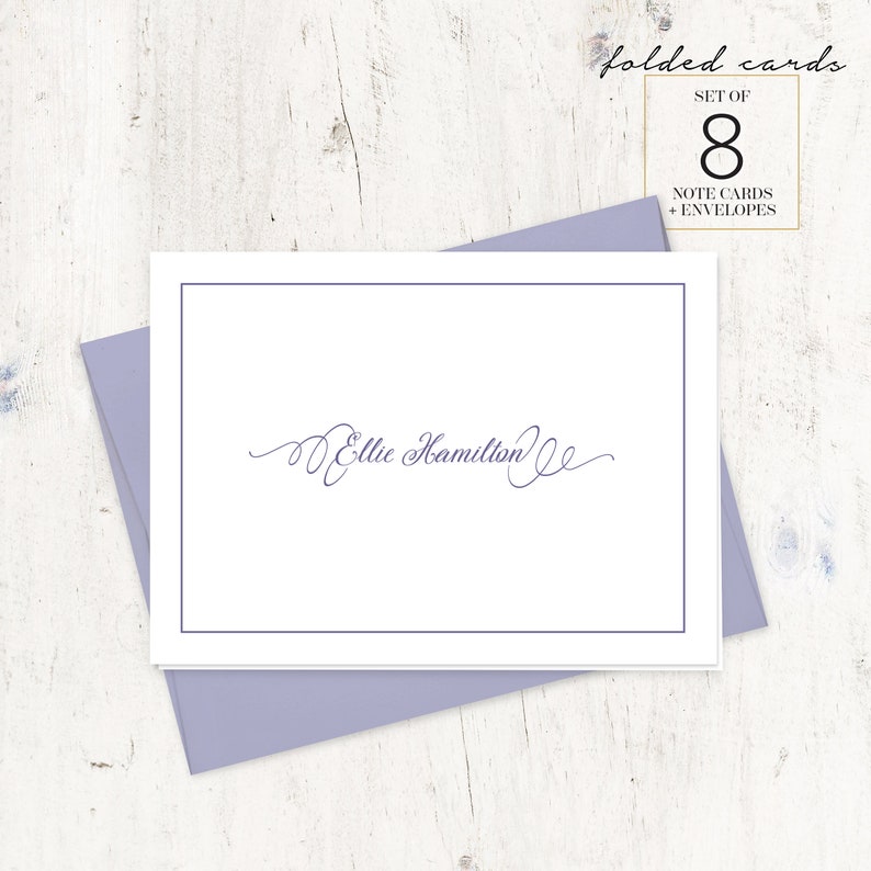 May include: A set of 8 folded note cards with envelopes, featuring a white card with a blue border and the name "Ellie Hamilton" written in cursive script.