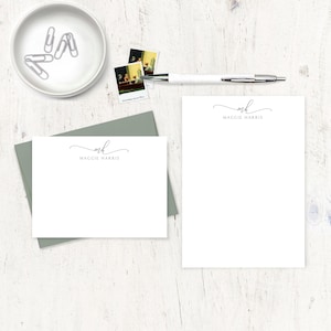 May include: Two white stationery note cards with a gray envelope. The note cards have a simple, elegant design with the initials "MH" and the name "Maggie Harris" in a script font.