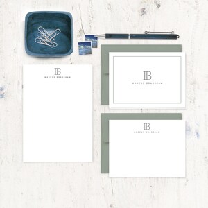 May include: Two white stationery cards with a gray envelope. The cards feature a simple monogram design with the initials "IB" and the name "Marcus Bradshaw" printed in gray.